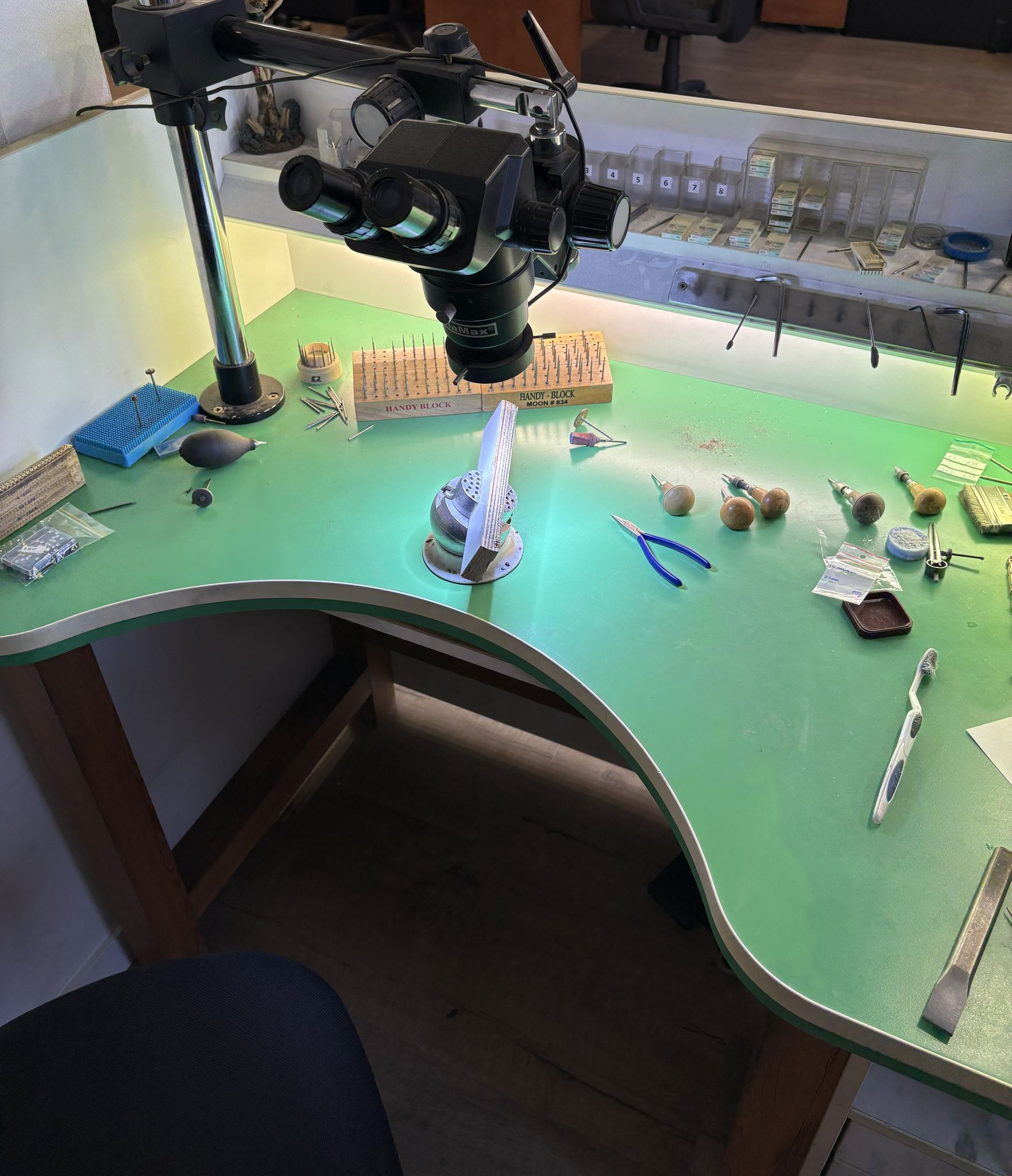 Overhead view of a setting workbench with tools and stereo microscope — SKJ Serti workshop, Antwerp